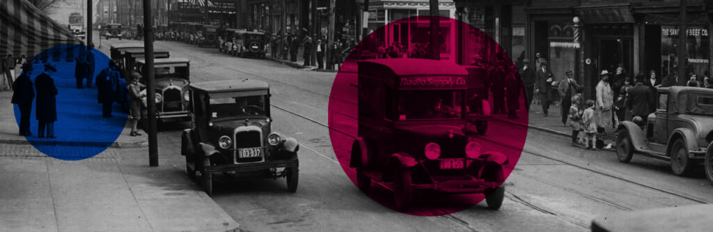 A photograph of "The Avenue" in Baltimore's Hampden neighborhood in the 1930s. 36th St or "The Avenue" features old cars and people walking around in suits.